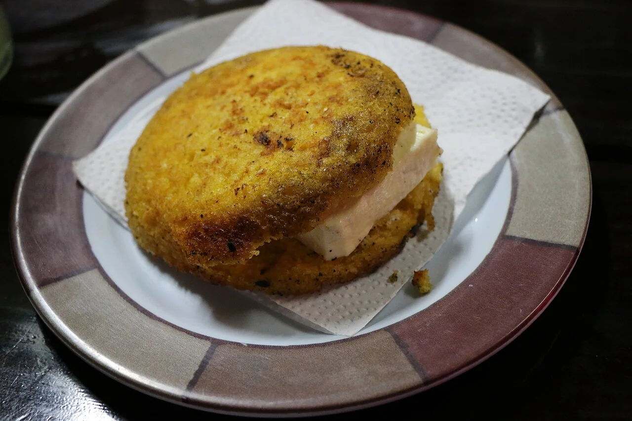 Arepa de chócolo colombiana dorada y acompañada de queso